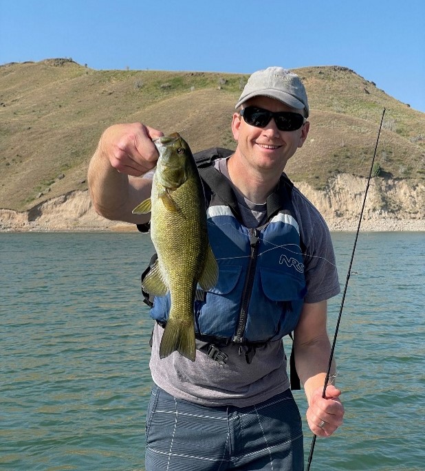 Man holding a sizeable small mouth bass at Ririe Reservoir
