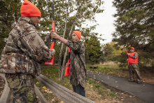 two girls passing rifles over a fence during a hunter education class October 2015