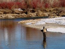 tight shot of an angler fishing on the South Fork of the Snake river in the Winter with snow on the river bank
